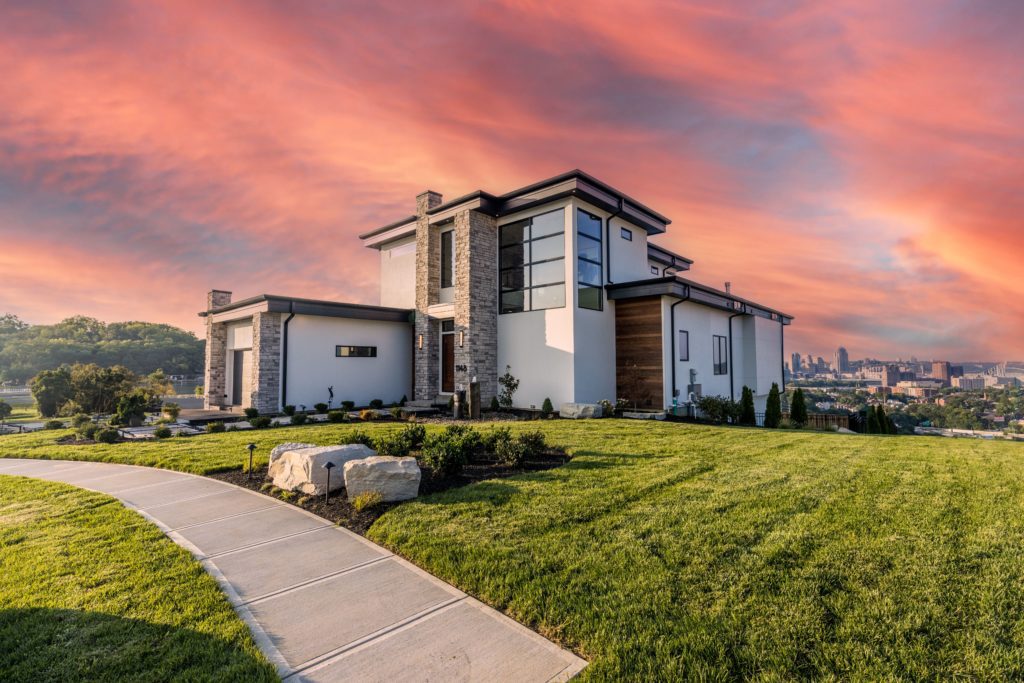 Twilight view of a custom home in Park Pointe, Park Hills, KY, showcasing warm lighting, landscaped front yard, and serene neighborhood setting.